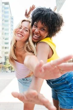 Vertical. Two happy young multiracial women laughing and gesturing at the camera Stock Photos
