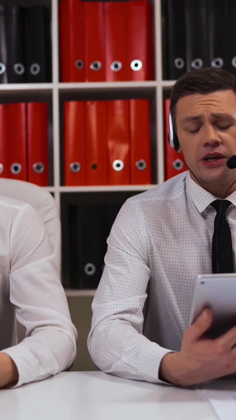 Vertical of Two male in call-centre talking with customers by headsets. Stock Footage 305517387