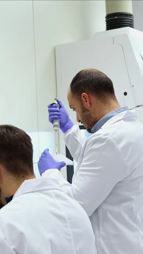 Vertical two Scientists using micropipettean microscope in laboratory resea.. Stock-Footage 296886292