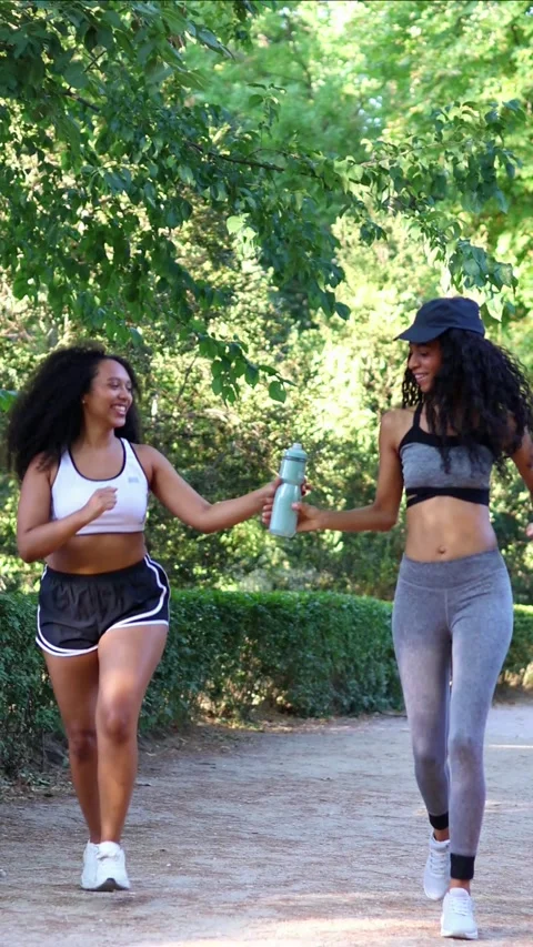 Vertical Two smiling multicultural Latin women running in a park Stock Footage 316259193