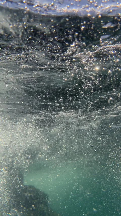 Vertical underwater tidal wave moves above a rock creating air bubbles beneath Stock-Footage 335206125