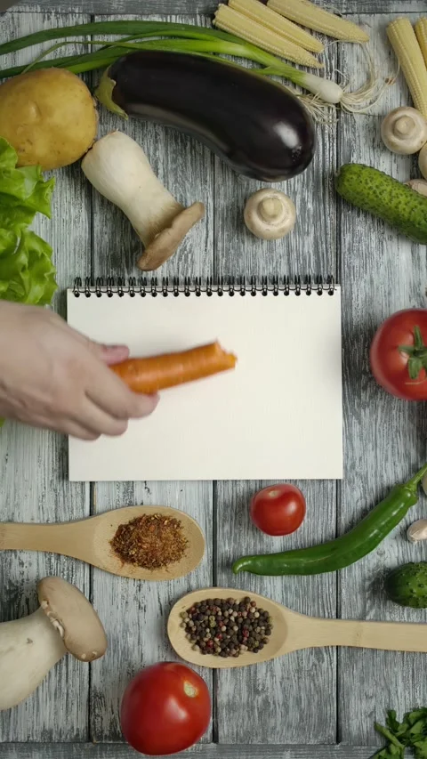 Vertical of Unrecognizable chef eats carrot while looking at recipe Stock Footage 276928791