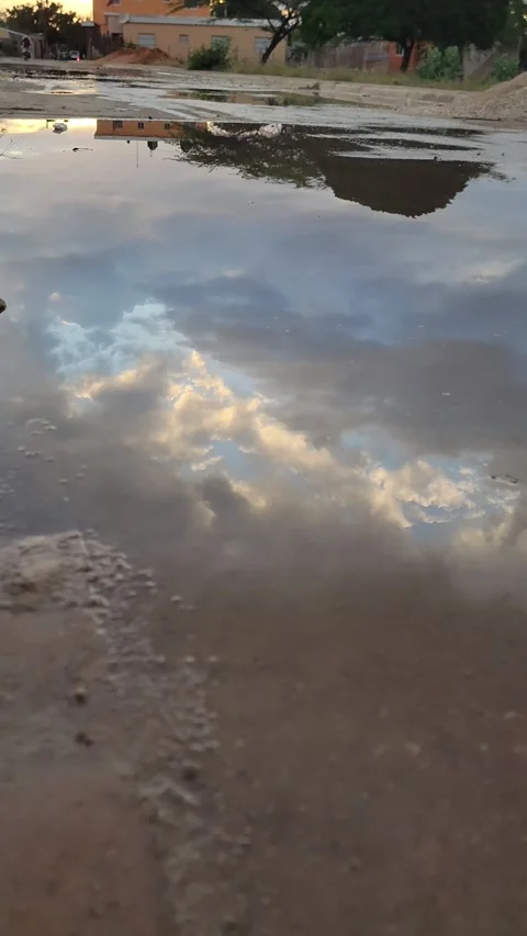 Vertical urban puddle reflecting red and blue sunset sky with dramatic clouds 스톡 동영상 329076288