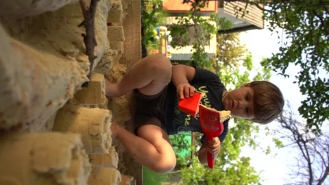 Vertical video, 4 years old kid play in a sandbox, little boy play with plastit Stock Footage 155163539