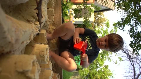 Vertical video, 4 years old kid play in a sandbox, little boy play with plastic  Stock Footage 155163570
