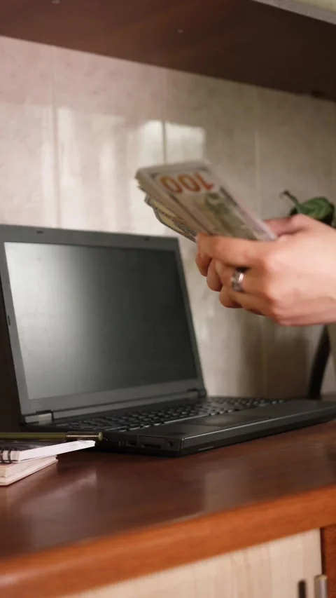 Vertical video 9:16 fanning stack of 100 dollar bills near laptop Stock Footage 344058015