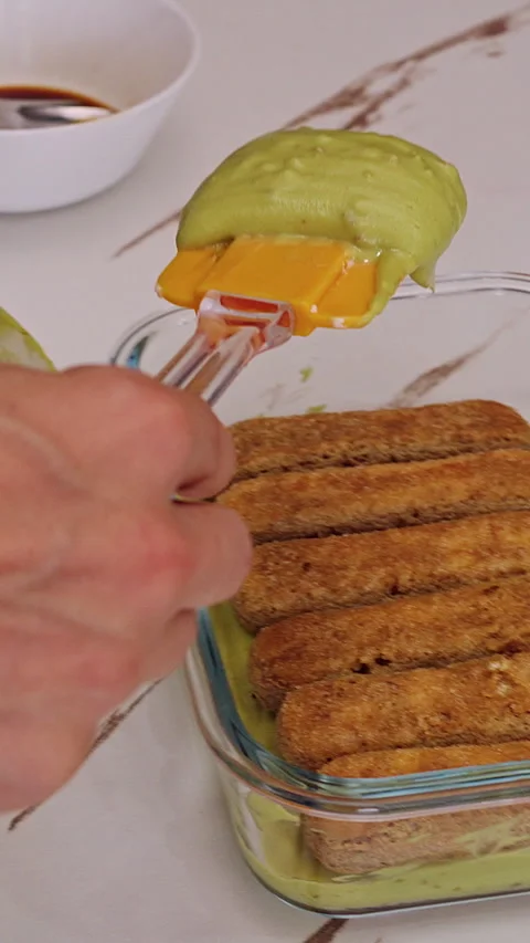 Vertical video. Adding Layer Of Savoiardi Biscuits Into Glass Dish With Green Cr Stock Footage 326660627