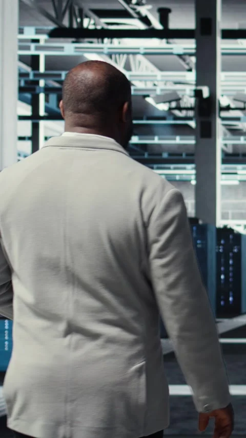 Vertical video Admin walking in high tech data center facility with rows of Stock Footage 311489484