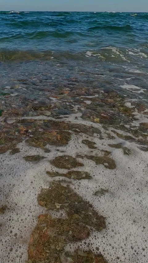 Vertical video, Aerial view, Camera flies up from a pebble shore in a coastal Stock Footage 319818671