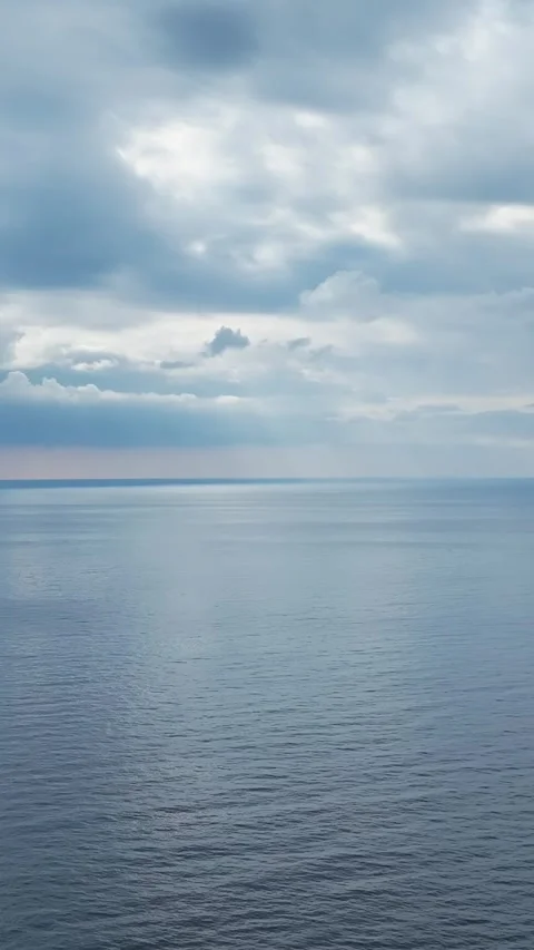 Vertical Video: Aerial View of a Cloudy Sunset With Blue Hues Over the Ocean and Stock Footage 342900539