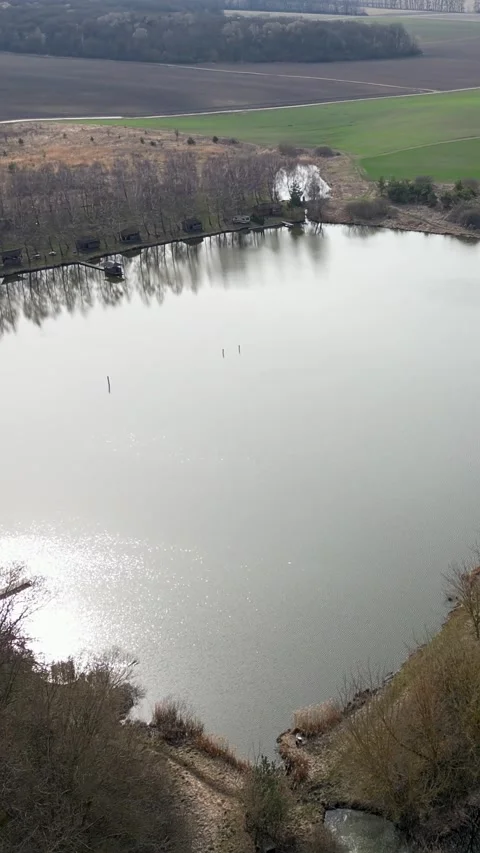 Vertical video. Aerial view flying over a lake with sun glistening on water Stock Footage 332047076