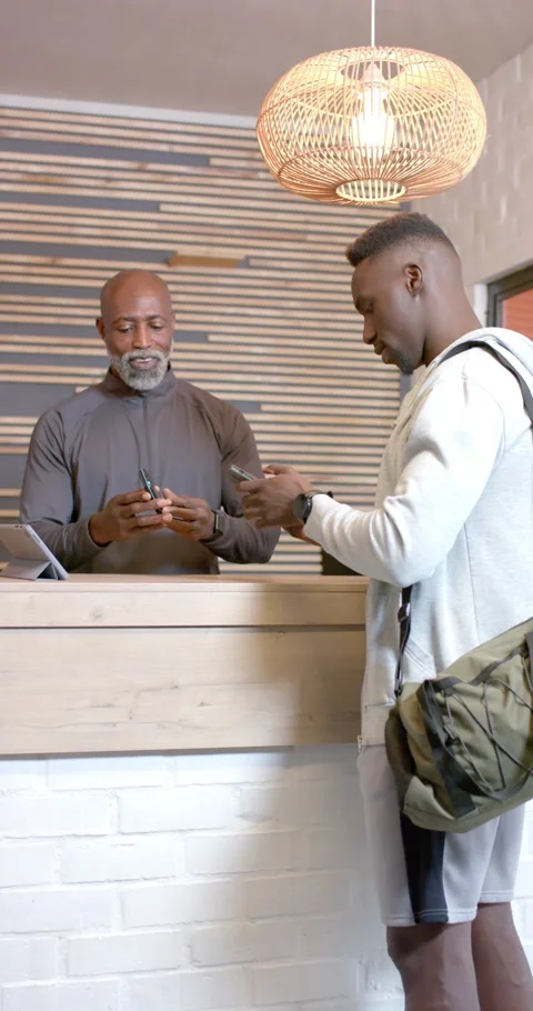 Vertical video: African American client showing QR code on phone and clerk Video stock 345128961