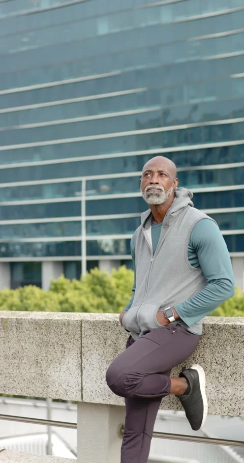 Vertical video: African American man leaning on terrace wall, scanning skyline Stock Footage 346718662