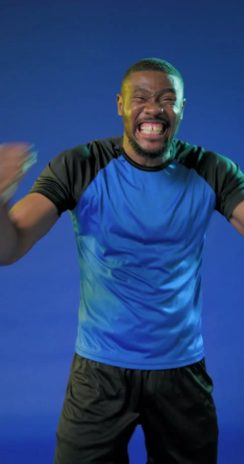 Vertical video: African man in blue shirt, black shorts yelling punching cam Stock Footage 345130843