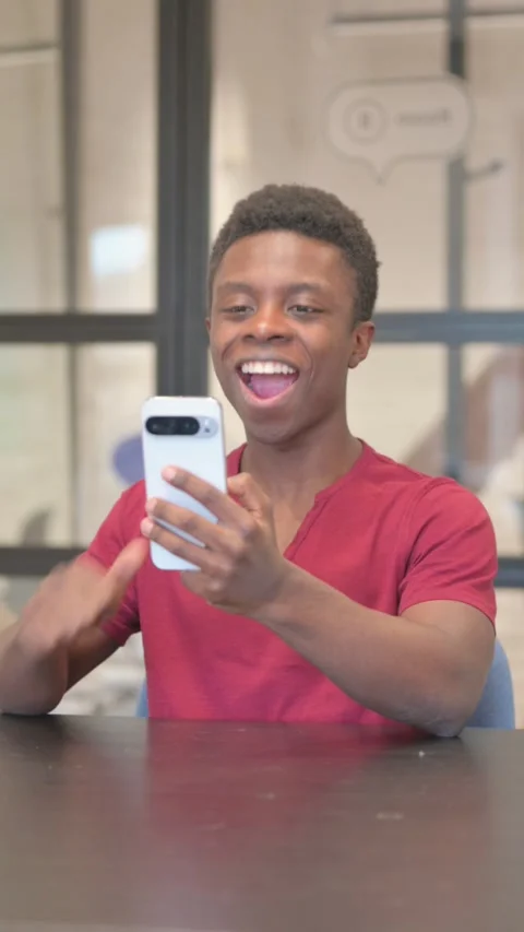 Vertical video of African Man Doing Video Chat on Phone in Office Stock Footage 303218536