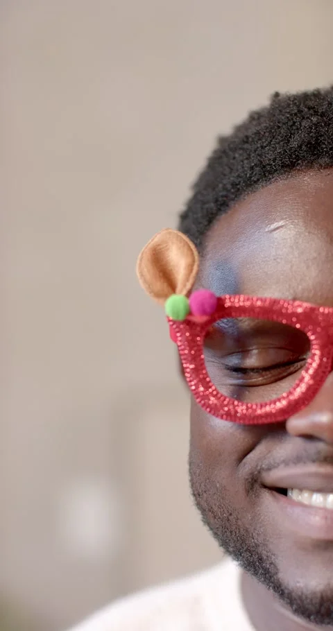 Vertical video: African man noticing camera smiling opening eye at home with red Stock Footage 345092665