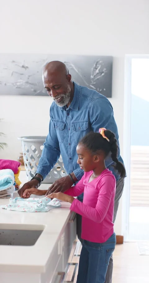 Vertical video: African man picking garment from laundry basket, teaching child Vídeo Stock 345322211