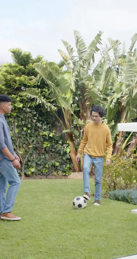 Vertical video: After ball taps, Diverse male friends dribbling football for Stock-Footage 345217699