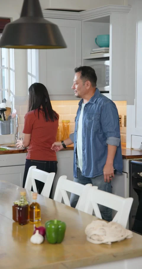 Vertical video: After tap Asian couple prepping kitchen rinsing bouquet for vase Stock-Footage 345216886