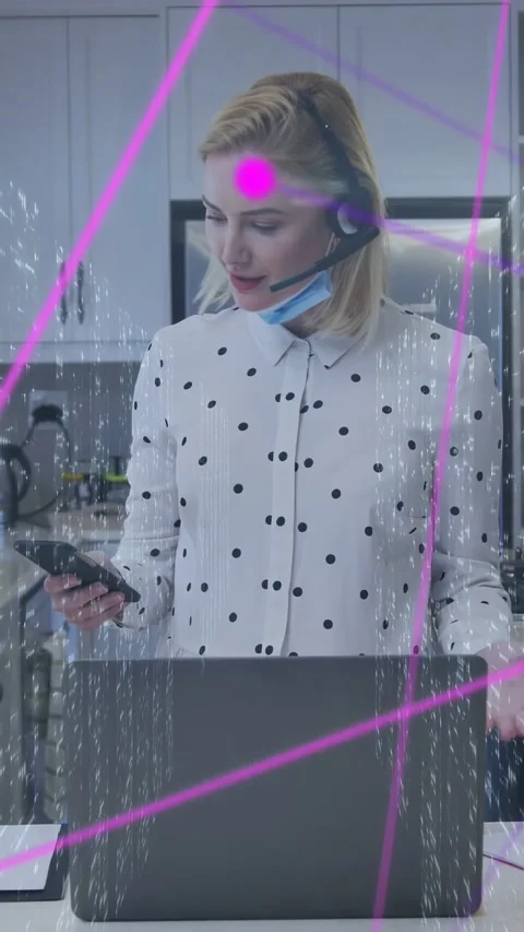 Vertical video: Agent taking tech call, holding phone at laptop, neon overlay Stock Footage 333603704