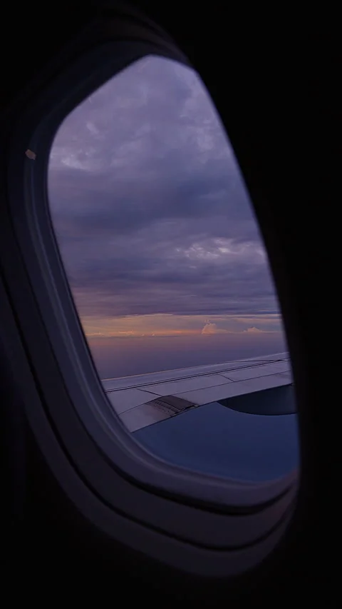 Vertical video. Airplane Window View of Wing and Cloudy Evening Sky Above the Oc Stock Footage 336557468