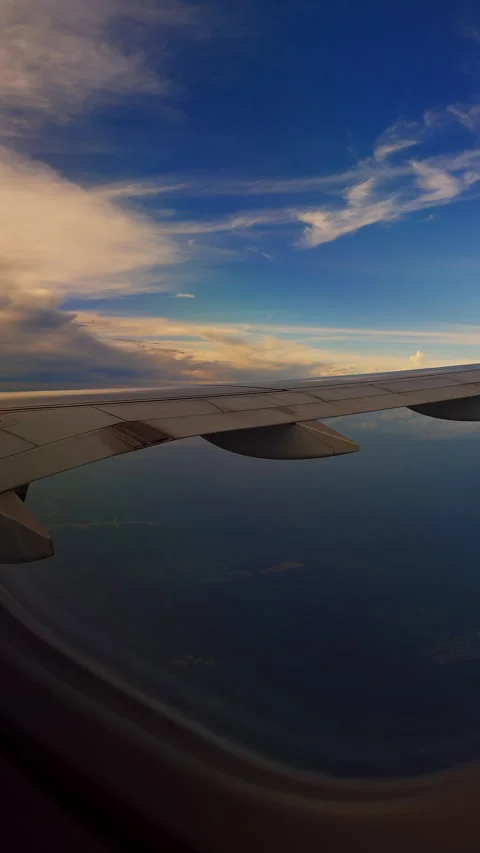 Vertical video. Airplane Wing Over Ocean Beneath Dramatic Clouds During Sunset F Stock Footage 337150684