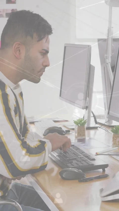 Vertical video: Analyst typing and leaning at dual monitors, causing animated Stock Footage 334601189