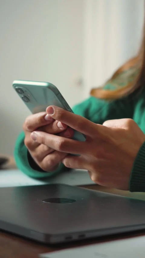 Vertical video of an anonymous woman’s hands using a smartphone and laptop. Tech Stock Footage 346330086