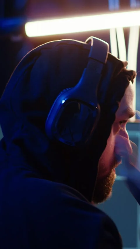 Vertical video Anxious hacker hiding in bunker removing headphones to hear Stock Footage 319519040