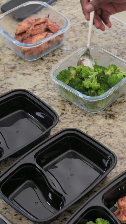 Vertical video: Arm scooping broccoli adding chicken on kitchen counter with Stock Footage 348637088