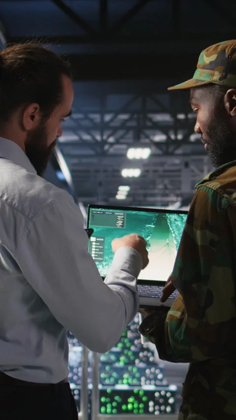 Vertical video Army operators in data center using laptop to run drone control Stock Footage 310774221