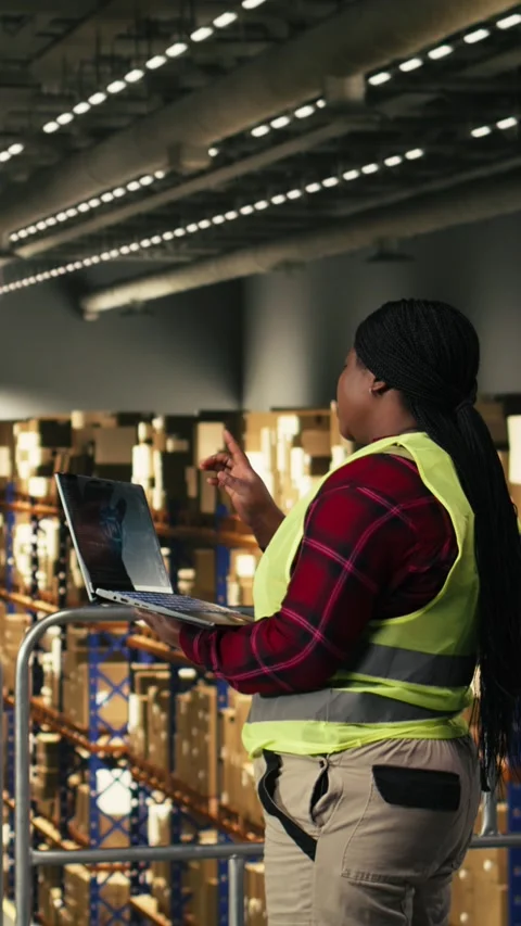 Vertical Video Artificial intelligence on laptop, black woman in warehouse 動画素材 330439805