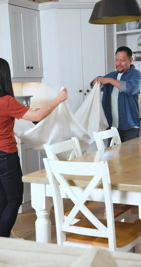 Vertical video: Asian couple taking white sheet from laundry basket, folding on Vídeo Stock 345040177