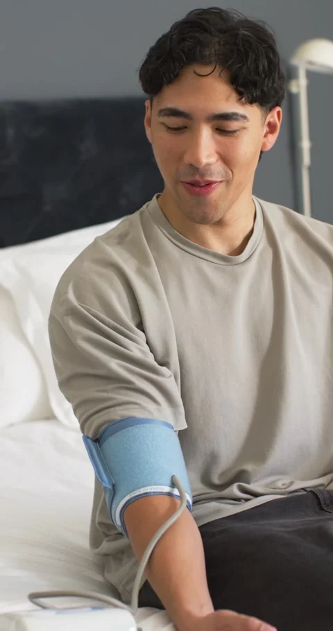 Vertical video: Asian man checking blood pressure on bed after fitting blue cuff Stock Footage 345219500