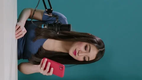 Vertical video: Asian vlogger reading comments with mobile phone on camera Stock Footage 177193124
