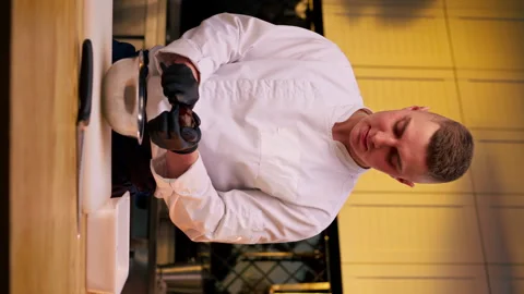 Vertical video assistant chef in the kitchen in white jacket cuts beets in his Stock Footage 273546855