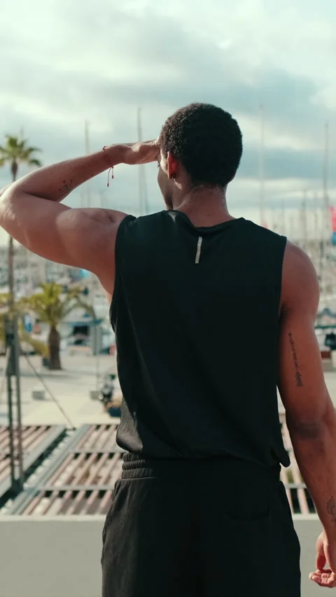 Vertical video, Athlete Overlooking a Harbor Full of Sailboats Stock Footage 313153902