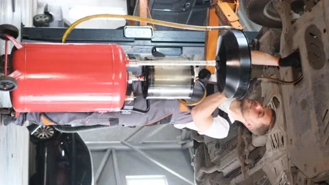 Vertical video. Auto mechanic under the car. Professional car repair in the Video stock 212346915