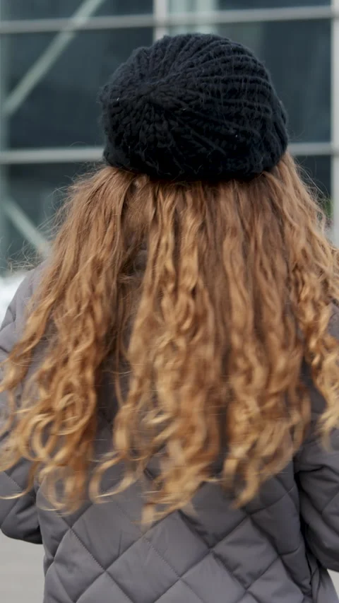 Vertical video of Back view on the curly hair young woman walking the town then Stock Footage 302254016