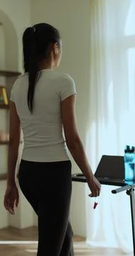 Vertical video. Back view Female is doing cardio workout training on treadm.. Stock Photos