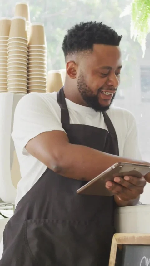 Vertical video: Barista tapping tablet and checking sales data at counter, Stock Footage 331720854