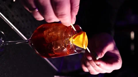 Vertical video the bartender decorates the cocktail with an orange bar Stock Footage 176391081