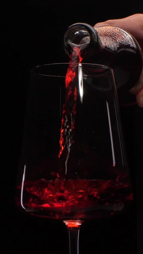 Vertical video Bartender pouring red wine into glass on black background Stock Footage 316210263