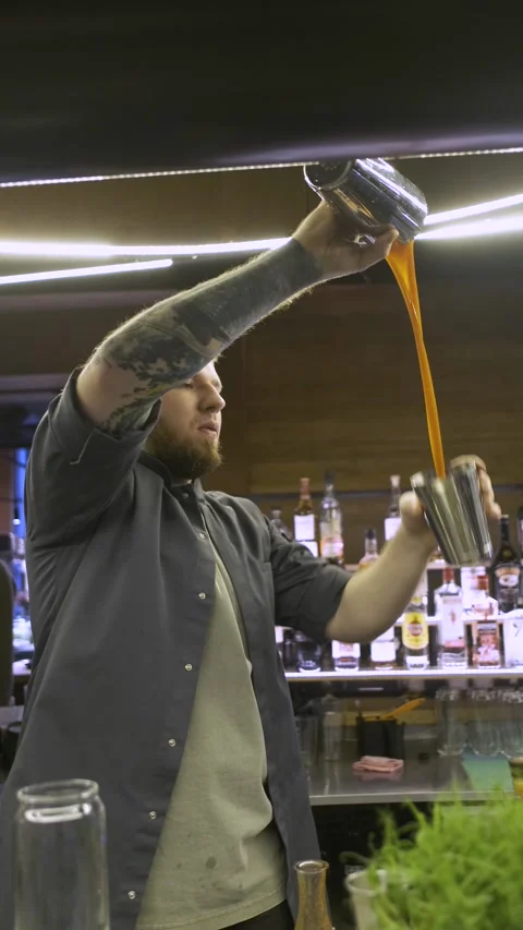 Vertical video, the bartender in the restaurant prepares a cocktail in a shaker Stock-Footage 247028760