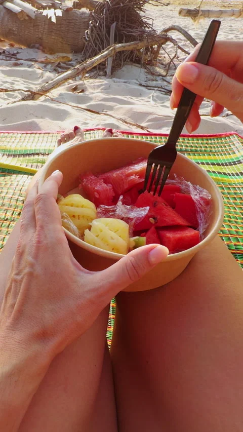 Vertical video. Beach Snack Moment, Hand Holding Watermelon Cube with Fork Above Stock Footage 332299794