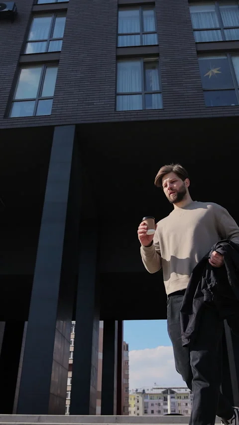 Vertical video. Bearded man running down stairs with coffee in hand Stock-Footage 344108920