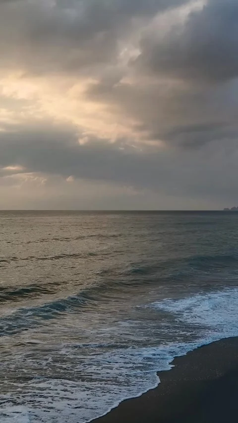 Vertical Video: Beautiful Cloudy Sky at Sunset Over the Ocean with Gentle Waves Stock Footage 297726122