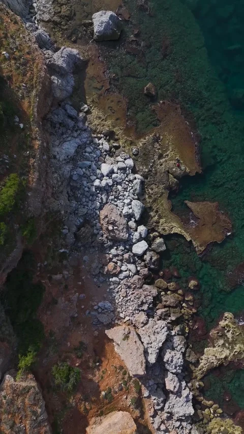 Vertical Video of a Beautiful Stone Beach With Clear Blue Water and Small Waves Stock Footage 301342750
