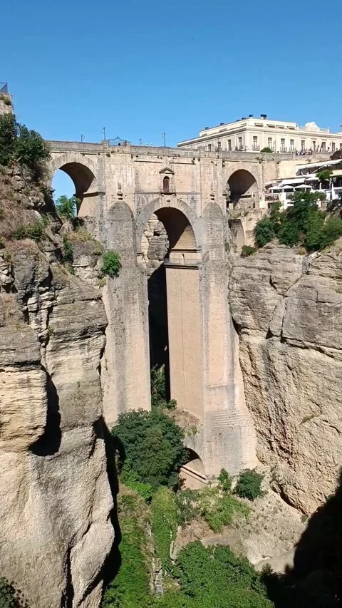Vertical video of the beautiful sunlit arched bridge over the Guadalevín River Stock Footage 344577746