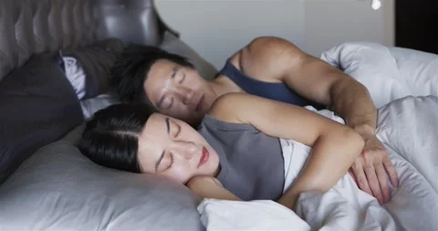 Vertical video: Bedtime leading couple settling into spooning man shifting arm Stock Footage 344385385